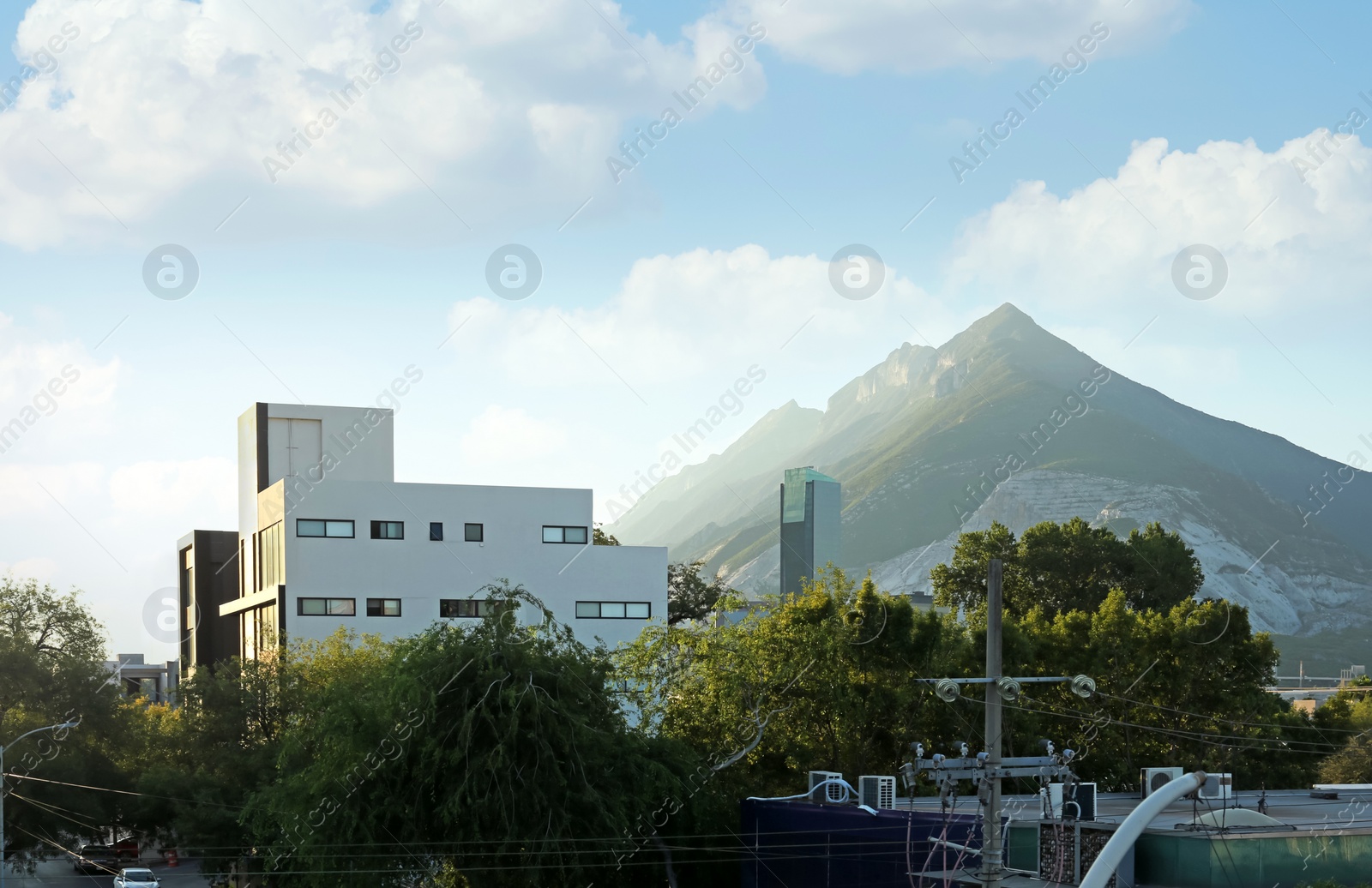 Photo of Picturesque view of cityscape with beautiful buildings and trees near mountains