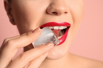 Photo of Young woman with ice cube on color background, closeup