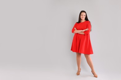 Photo of Beautiful overweight woman in red dress on light grey background. Space for text