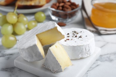 Photo of Tasty brie cheese on white marble table