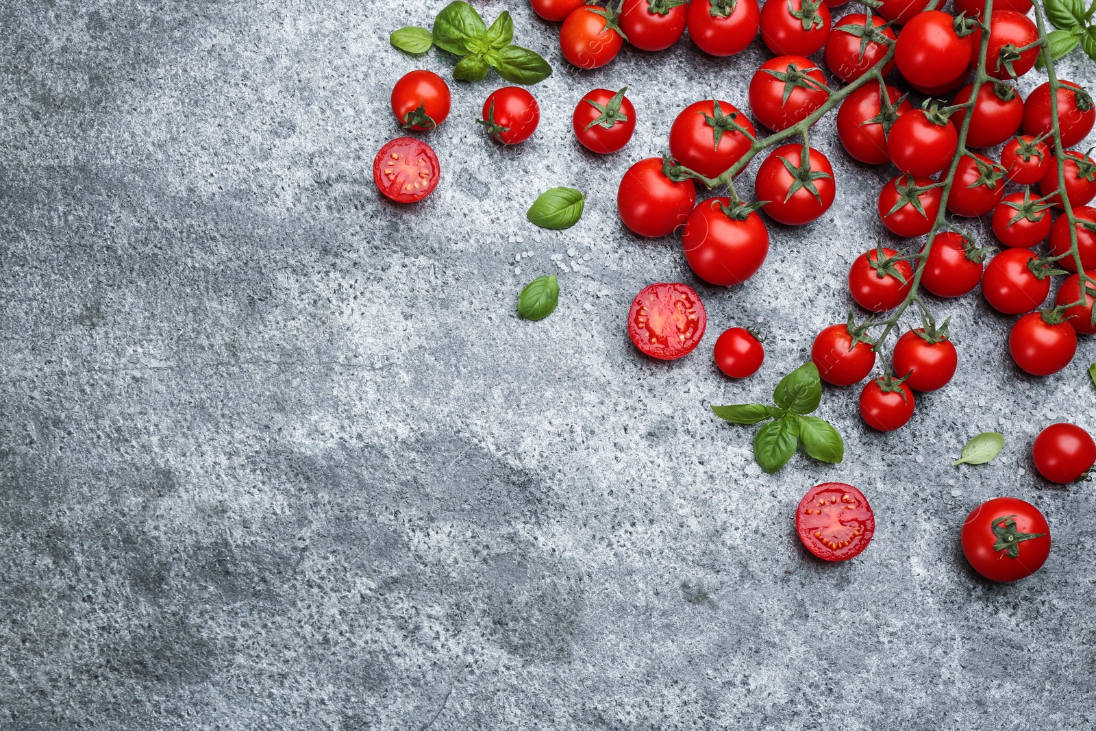 Photo of Fresh cherry tomatoes and basil leaves on grey table, flat lay. Space for text