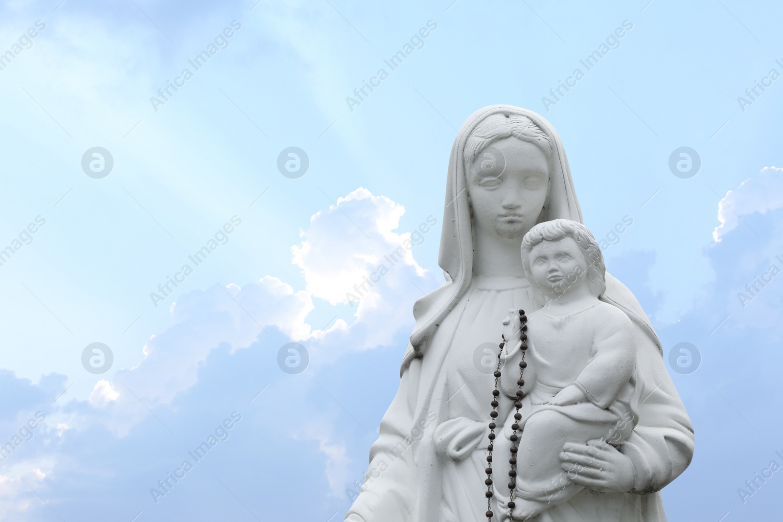 Photo of Beautiful statue of Virgin Mary and baby Jesus with rosary beads outdoors. Space for text