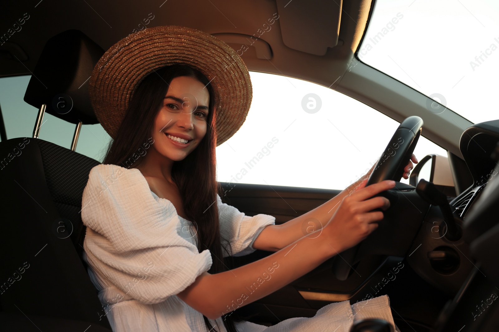 Photo of Beautiful young woman sitting in her car, low angle view. Enjoying trip