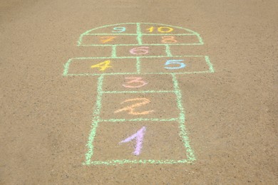 Photo of Hopscotch drawn with colorful chalk on asphalt outdoors
