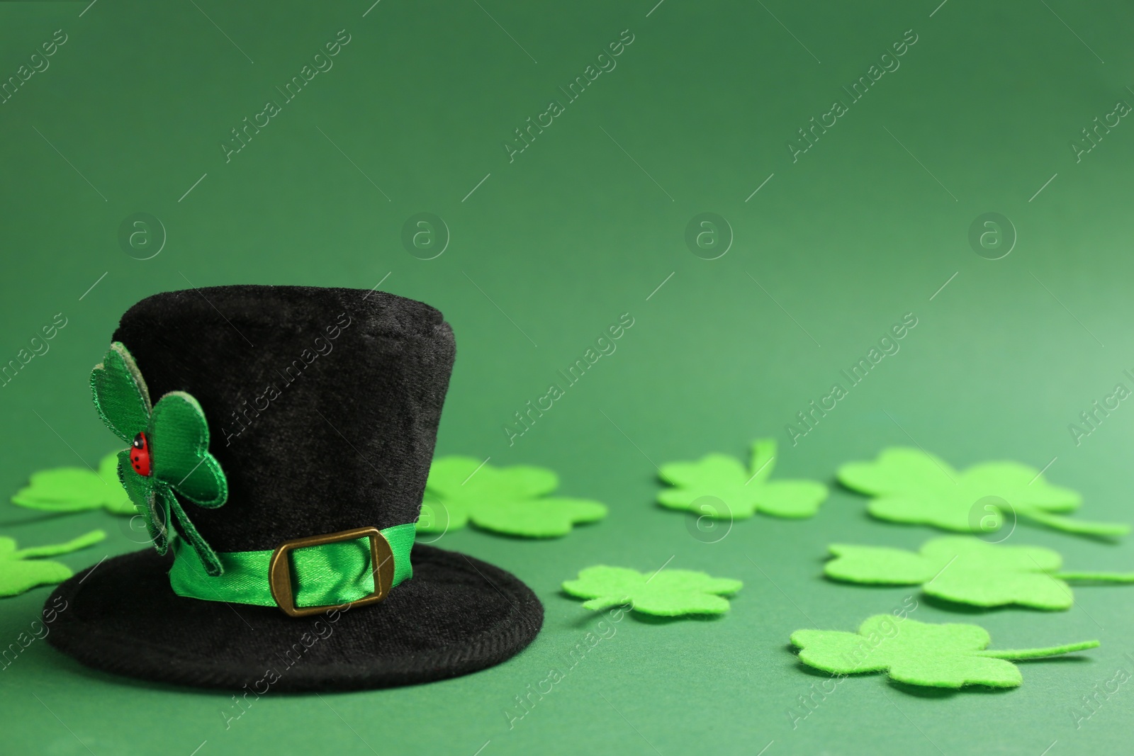 Photo of Leprechaun's hat and decorative clover leaves on green background. St. Patrick's day celebration