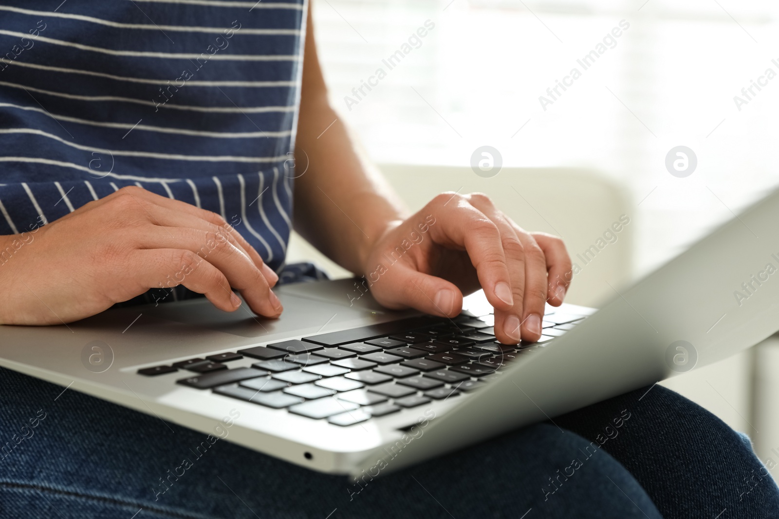 Photo of Young woman using laptop for search indoors, closeup