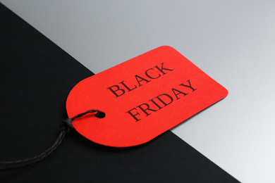 Red tag with words BLACK FRIDAY on color background, closeup