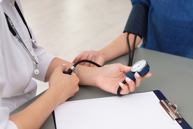 Doctor checking patient's blood pressure in hospital