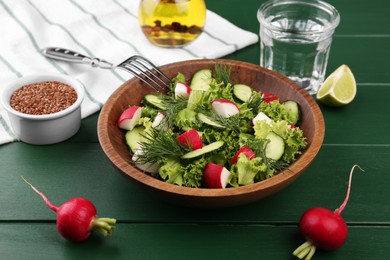 Photo of Delicious salad with radish, lettuce, dill and cucumber served on green wooden table