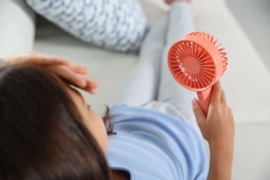 Photo of Little girl with portable fan suffering from heat at home. Summer season