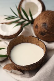 Photo of Delicious vegan milk in coconut and pieces of ripe fruit on white table