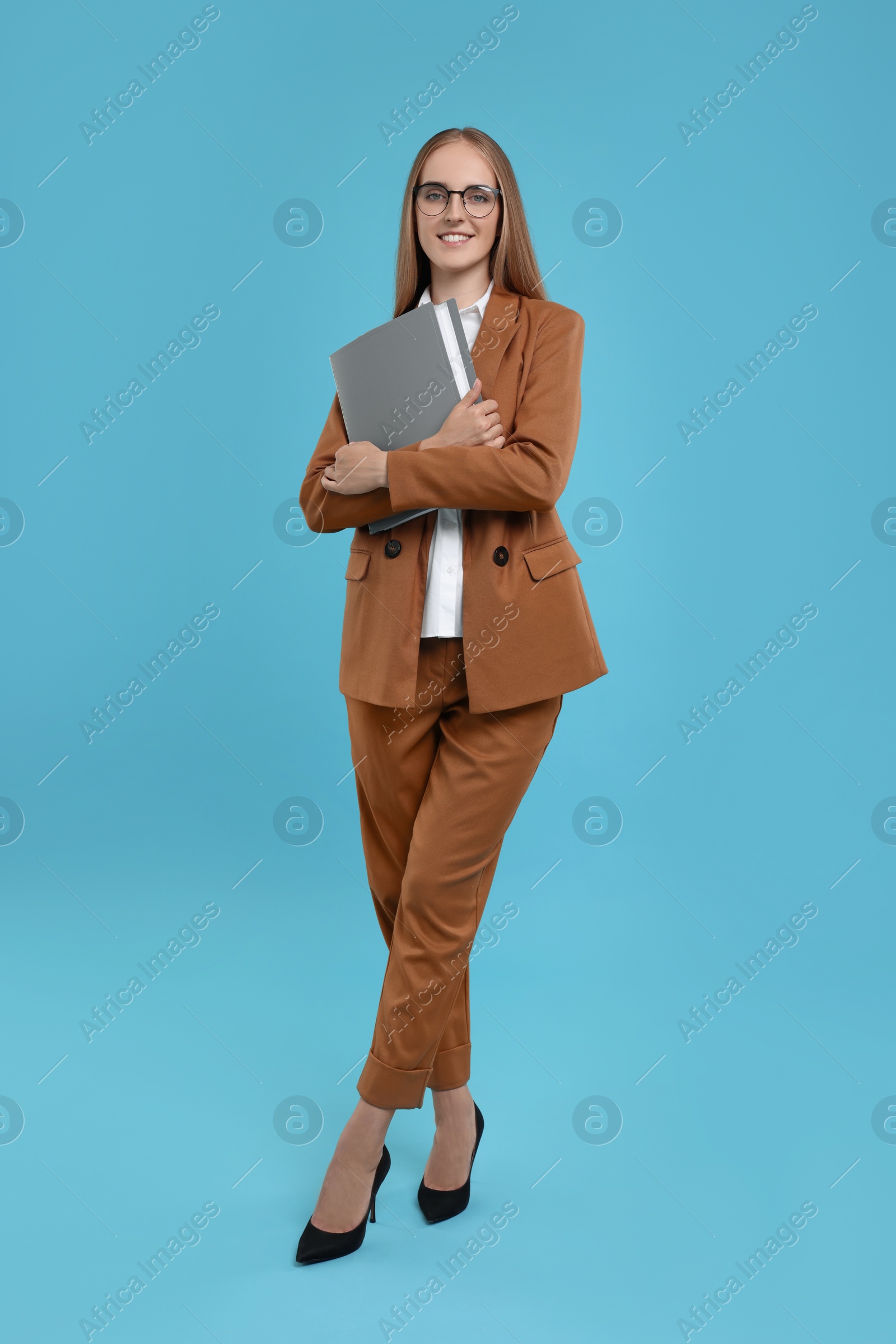 Photo of Happy young secretary with folder on light blue background