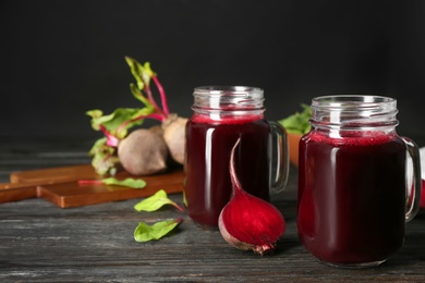 Photo of Fresh beet juice and raw vegetable on dark wooden table. Space for text
