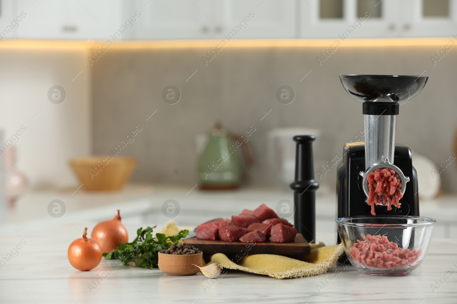 Photo of Electric meat grinder with beef mince and products on white table in kitchen