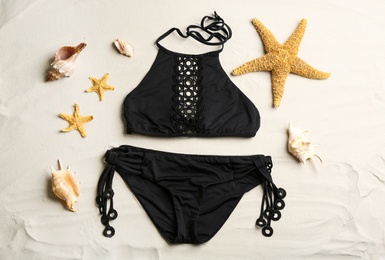 Flat lay composition with stylish swimsuit on sand. Beach accessory