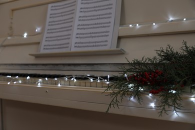 Photo of White piano with festive decor indoors, closeup. Christmas music