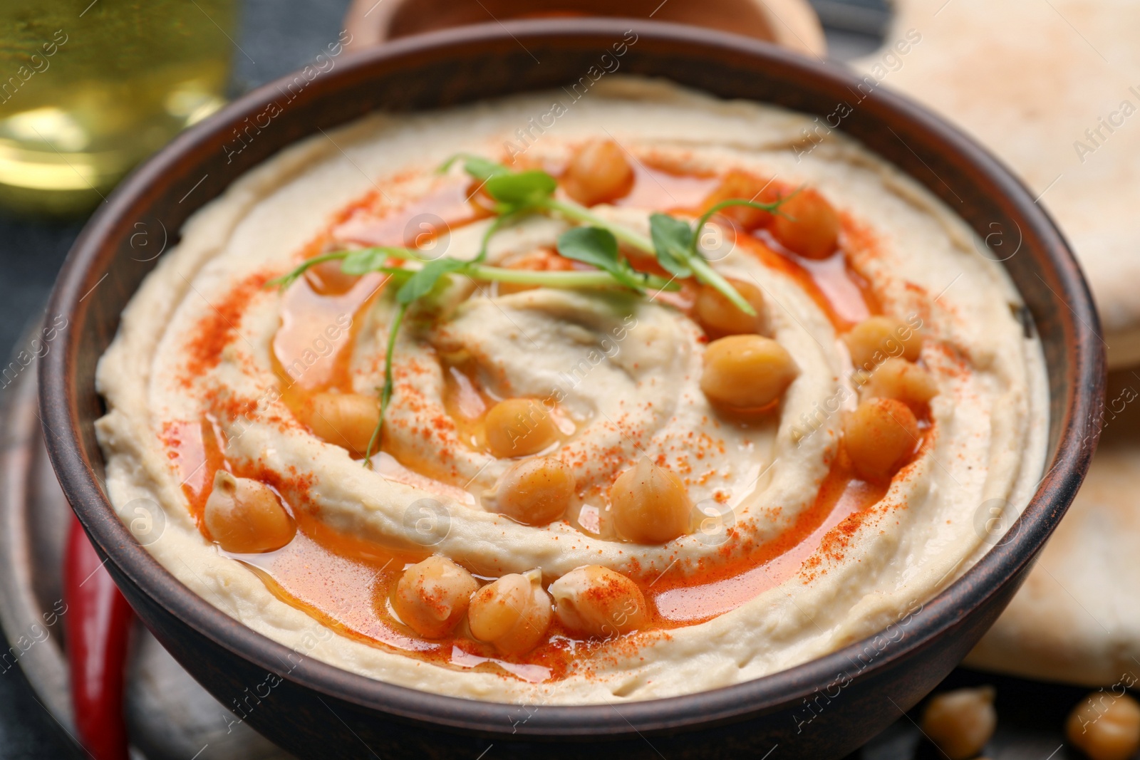 Photo of Bowl of delicious hummus with chickpeas on grey table, closeup