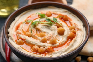 Bowl of delicious hummus with chickpeas on grey table, closeup