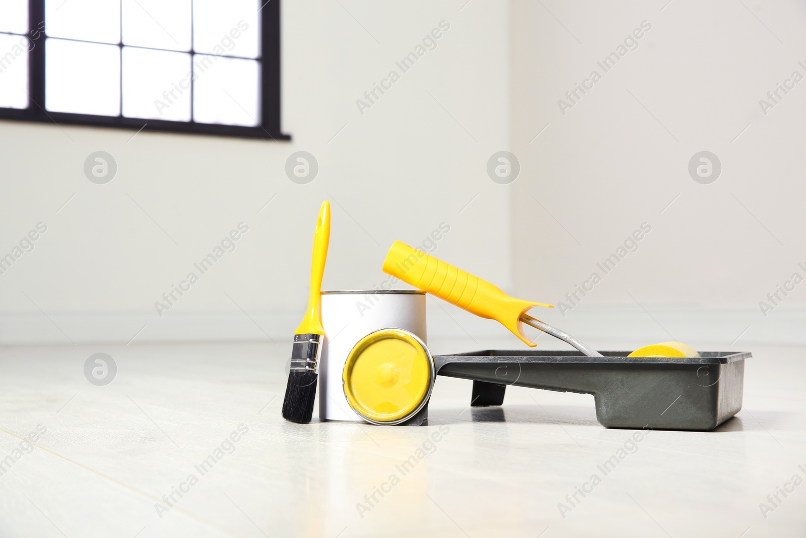 Photo of Can of paint and decorator tools on wooden floor indoors. Space for text