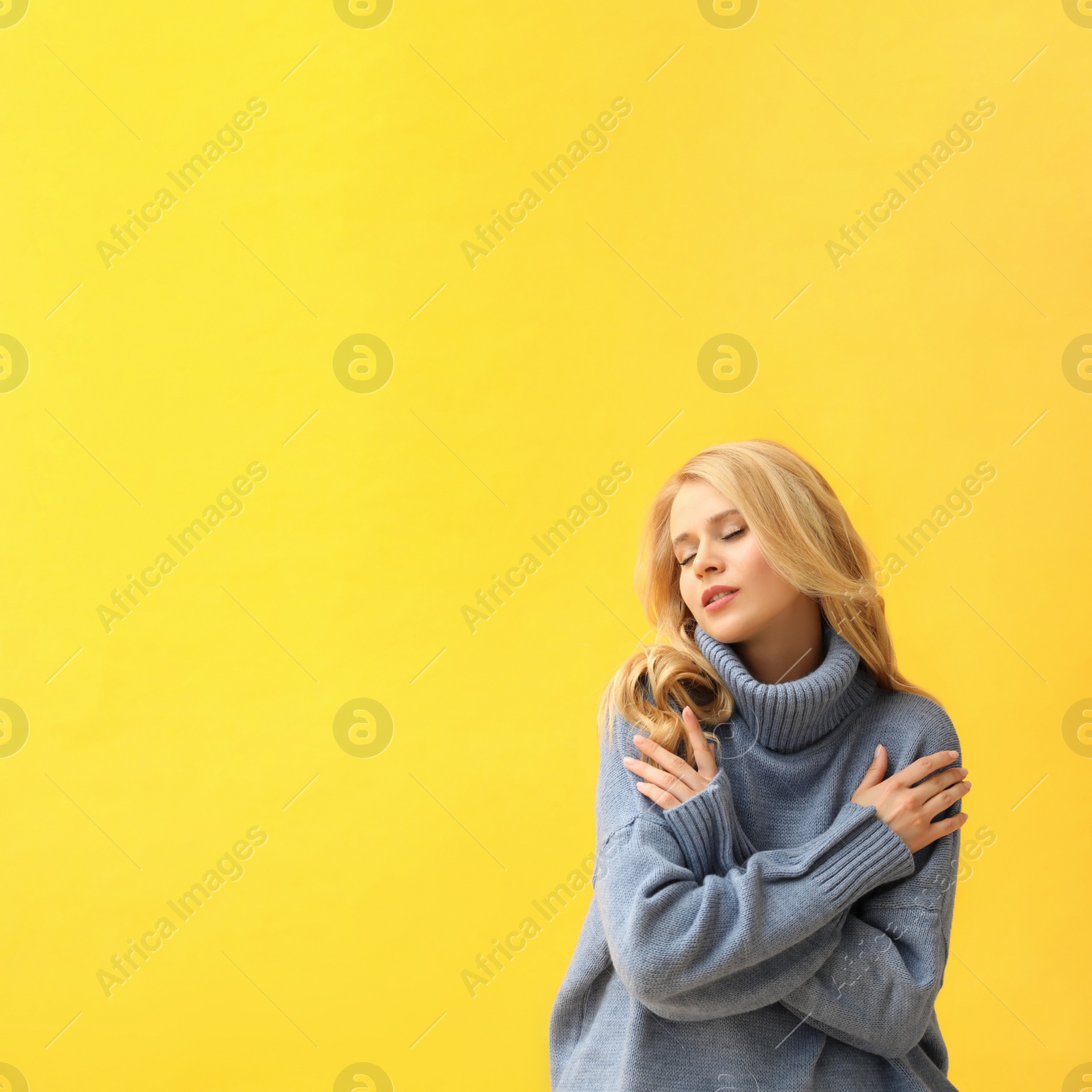 Photo of Beautiful young woman wearing warm blue sweater on yellow background. Space for text