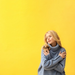 Beautiful young woman wearing warm blue sweater on yellow background. Space for text