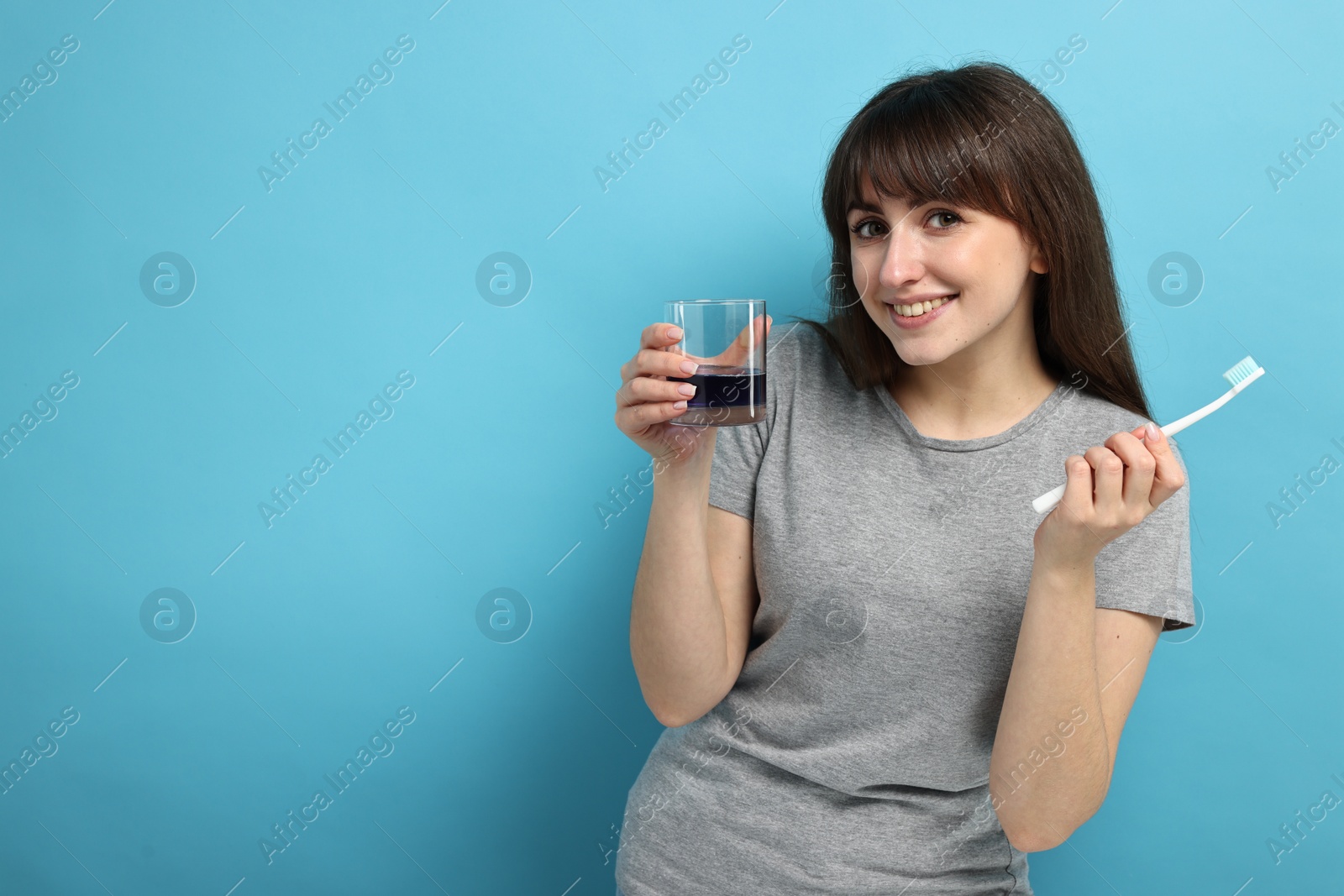 Photo of Young woman with mouthwash and toothbrush on light blue background, space for text