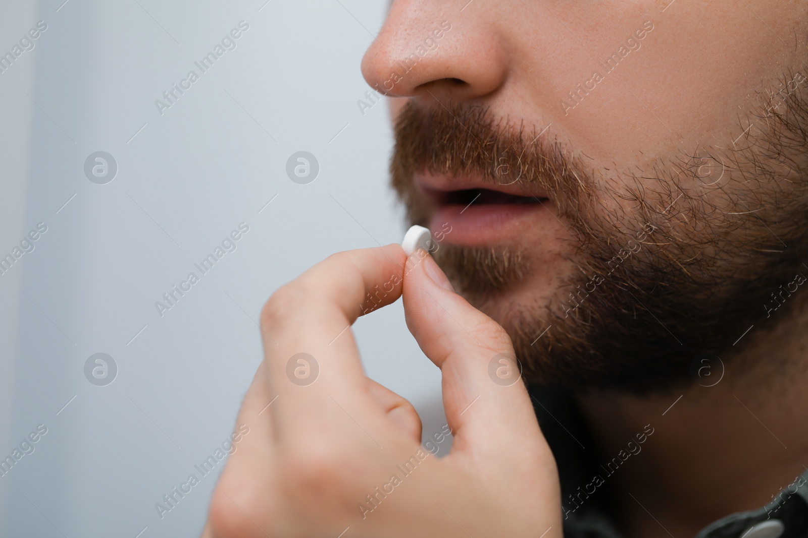 Photo of Man taking antidepressant pill on light background, closeup