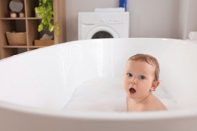 Photo of Cute little baby taking foamy bath at home. Space for text
