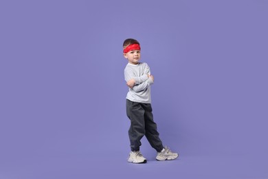 Photo of Happy little boy dancing on violet background