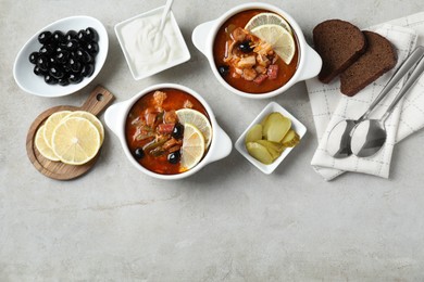 Meat solyanka soup with sausages, olives and vegetables served on white textured table, flat lay. Space for text