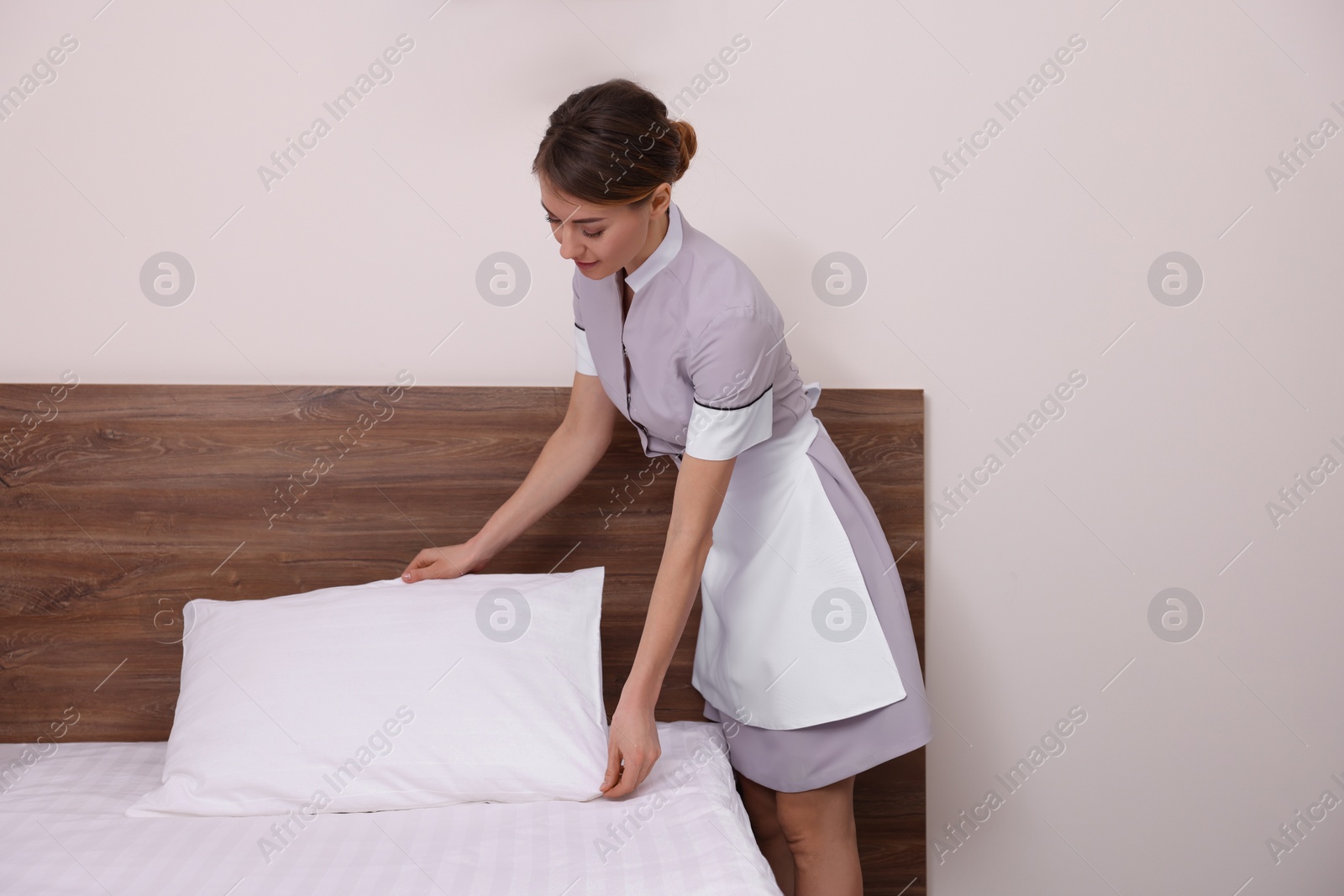 Photo of Beautiful chambermaid making bed in hotel room