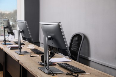 Photo of Open office interior. Modern workplaces with computers near light grey wall