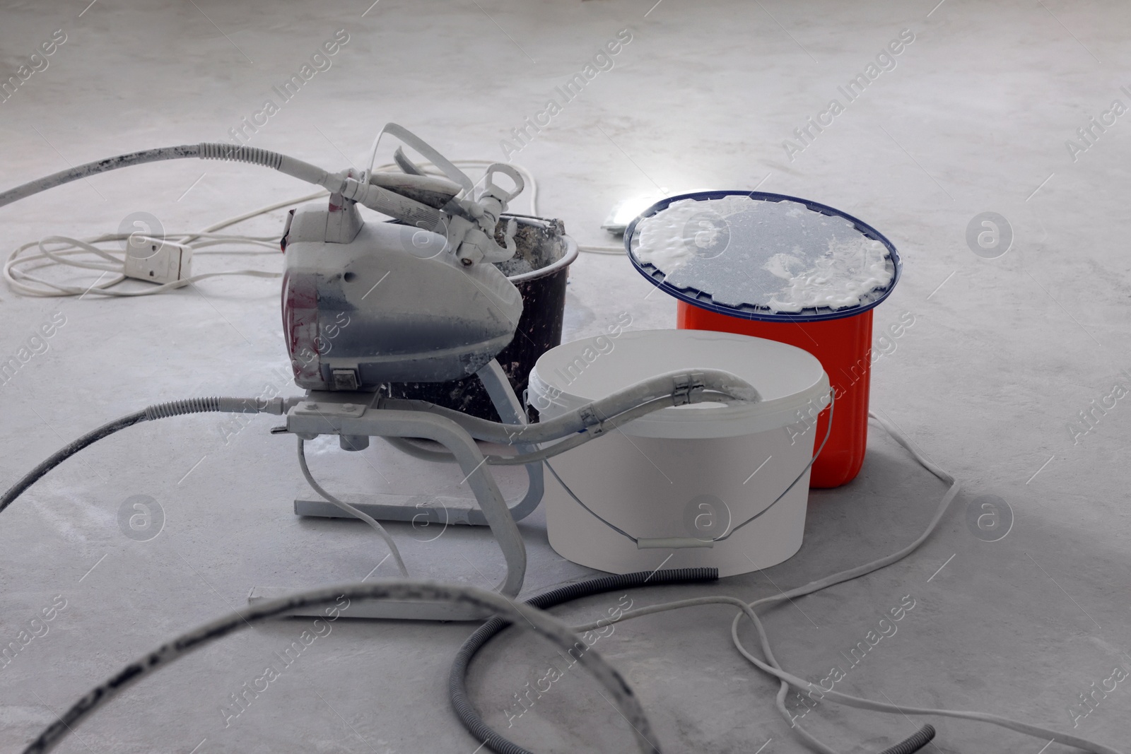 Photo of Paint sprayer near buckets on white floor