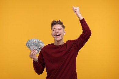 Photo of Happy man with dollar banknotes on yellow background