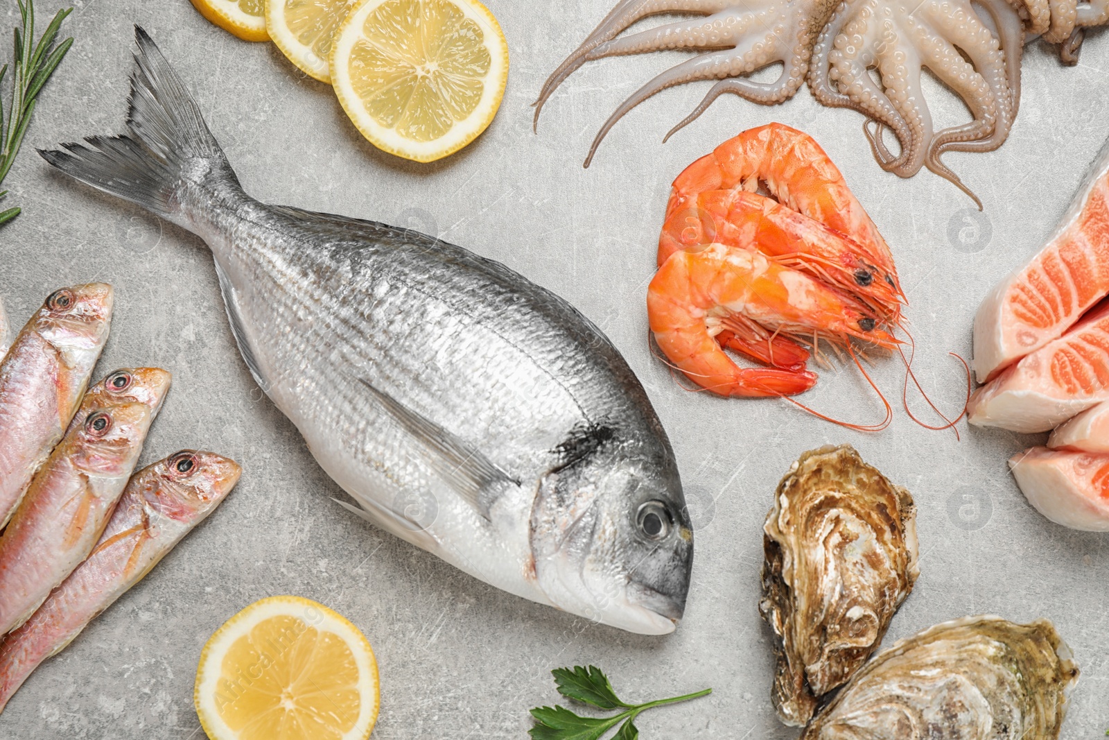 Photo of Fresh fish and seafood on light grey table, flat lay