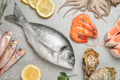 Photo of Fresh fish and seafood on light grey table, flat lay