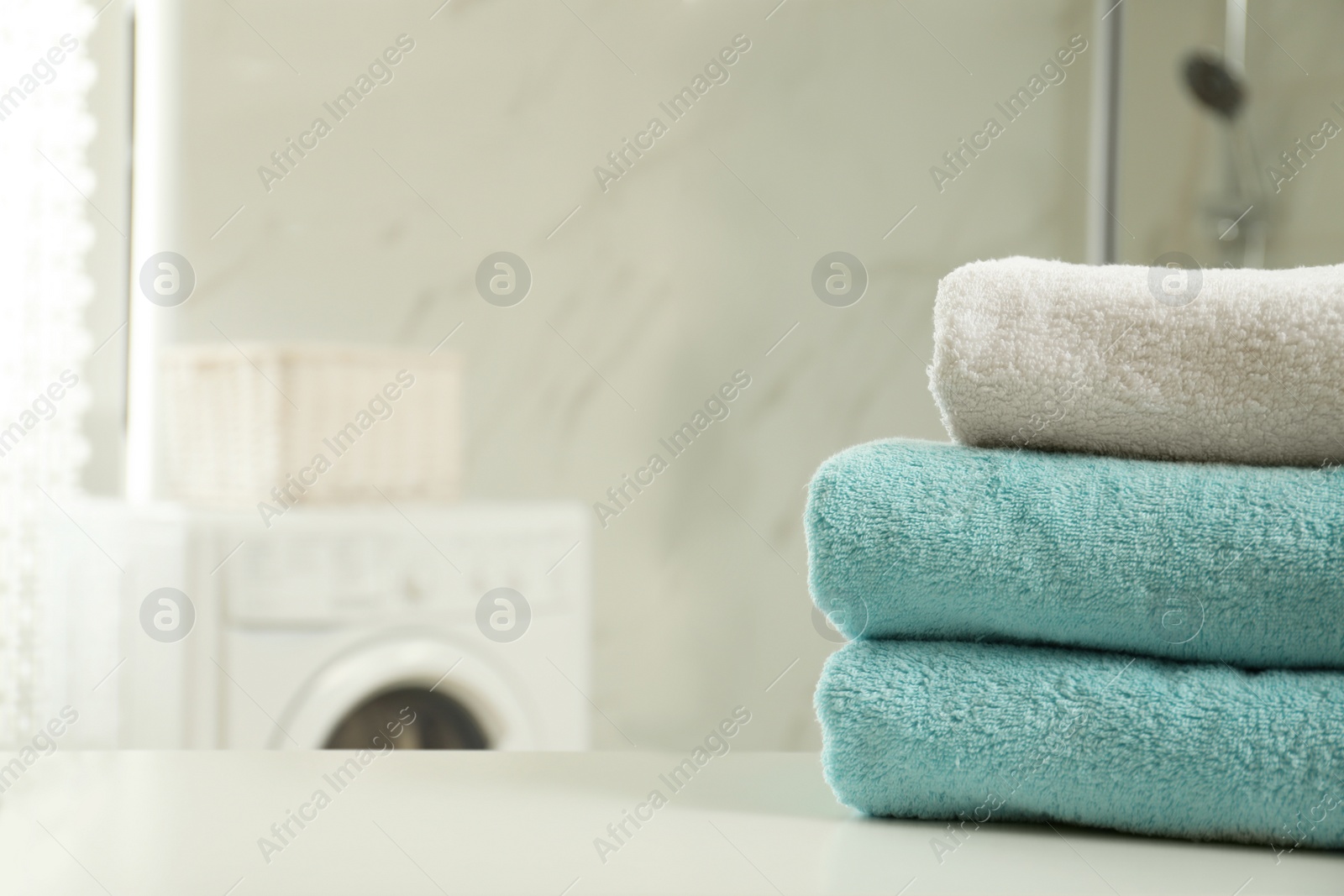 Photo of Stack of clean towels on table in laundry room. Space for text