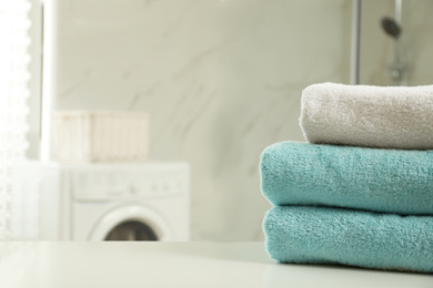 Stack of clean towels on table in laundry room. Space for text