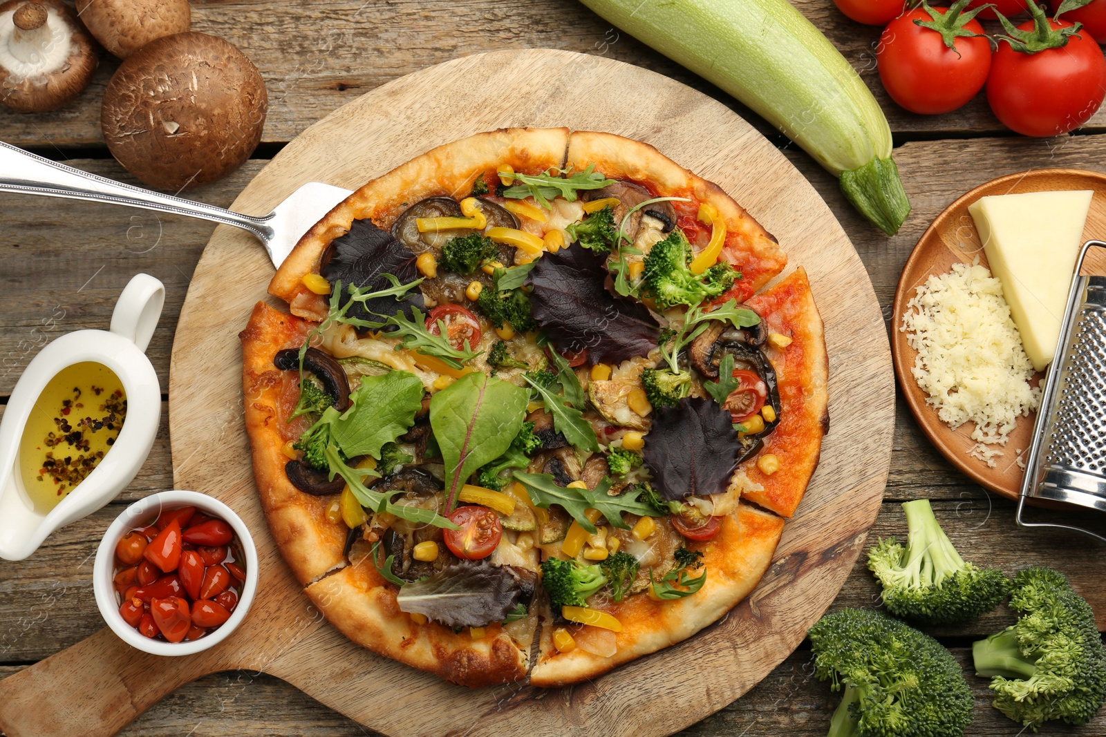 Photo of Delicious vegetarian pizza and ingredients on wooden table, flat lay