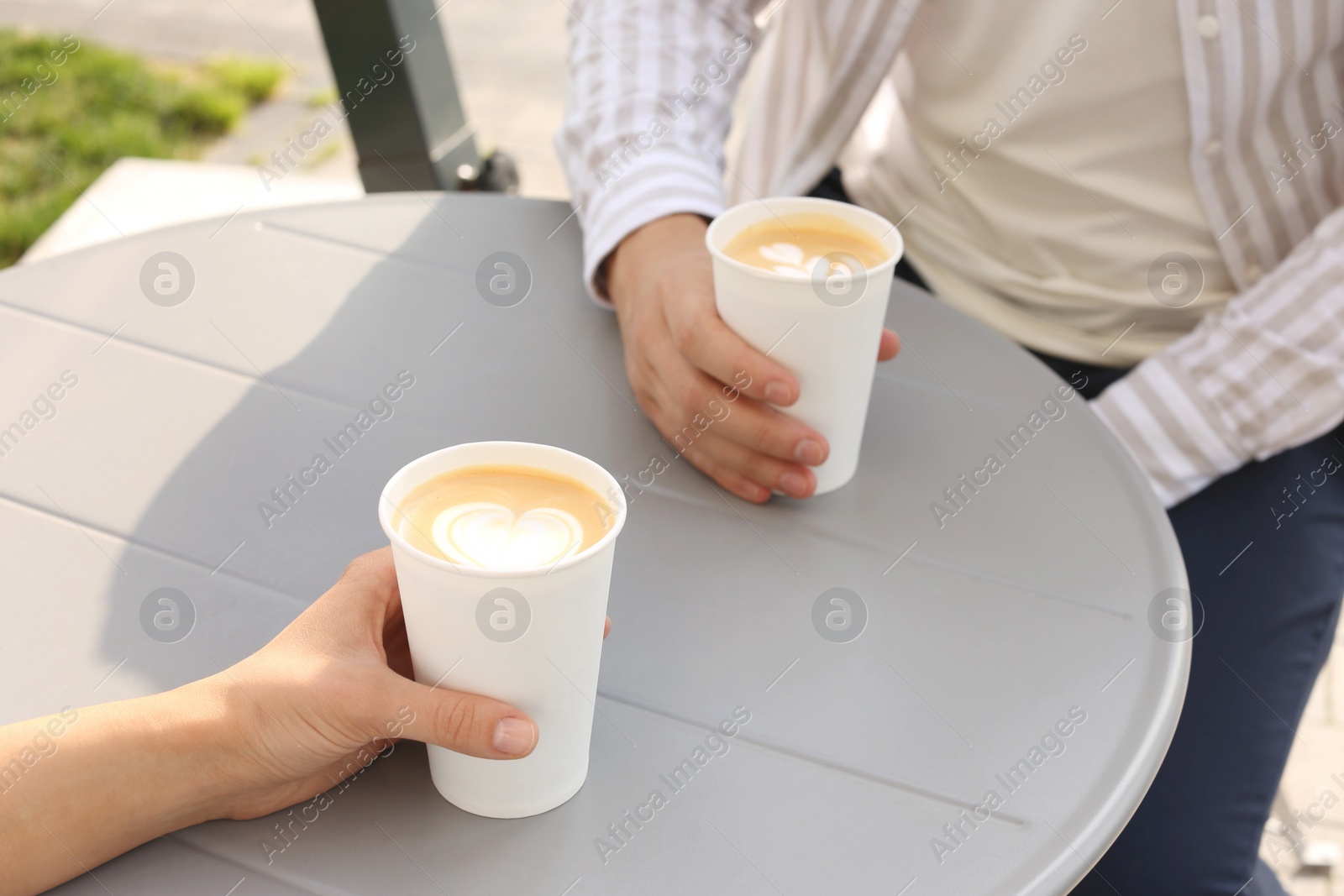 Photo of Coffee to go. Couple with paper cups at grey table outdoors, closeup