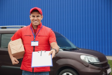 Courier with packages and clipboard near car outdoors, space for text