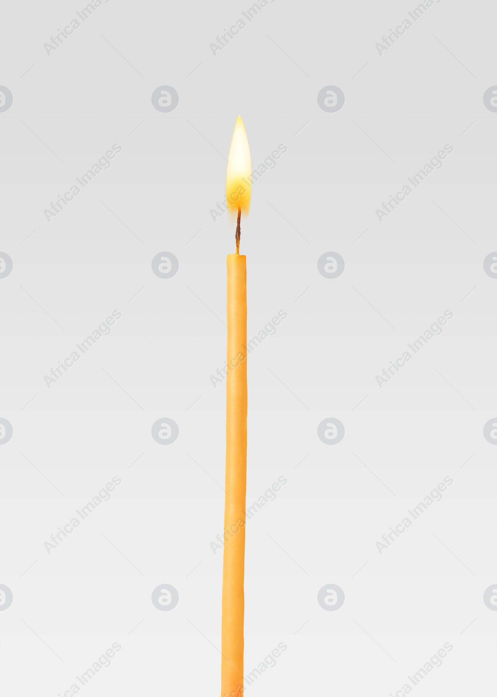 Image of One burning church candle on light background