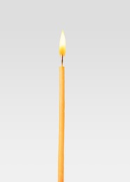Image of One burning church candle on light background