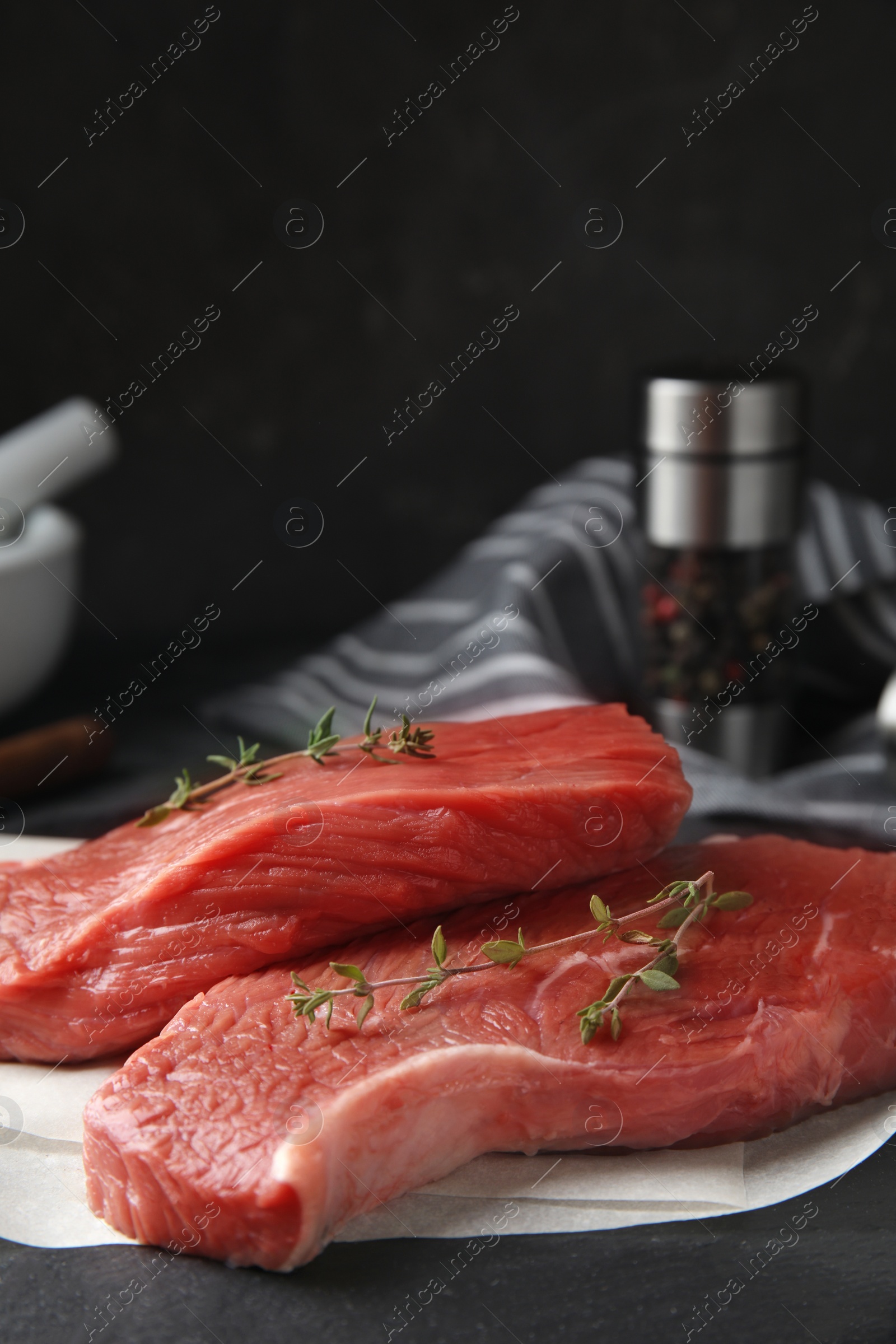 Photo of Fresh raw beef cut with thyme on black table