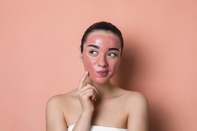 Photo of Woman with pomegranate face mask on pale coral background