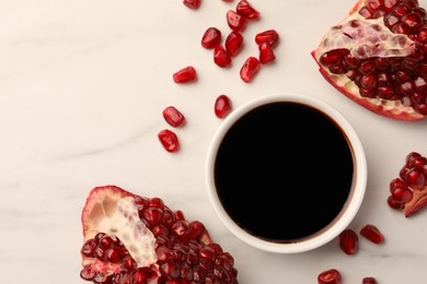 Photo of Bowl of pomegranate sauce and fresh ripe fruit on white marble table, flat lay. Space for text
