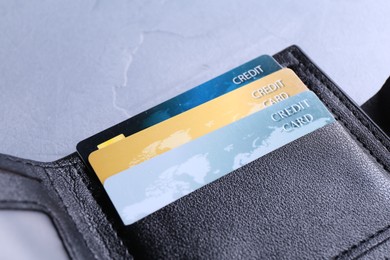 Credit cards in leather wallet on grey textured table, closeup