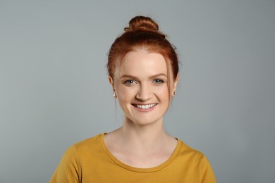 Photo of Candid portrait of happy red haired woman with charming smile on grey background