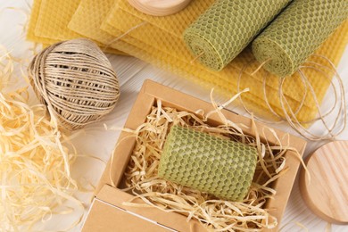 Photo of Stylish elegant beeswax candles, wax sheets and twine on white wooden table, flat lay