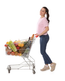 Photo of Happy woman with shopping cart full of groceries on white background